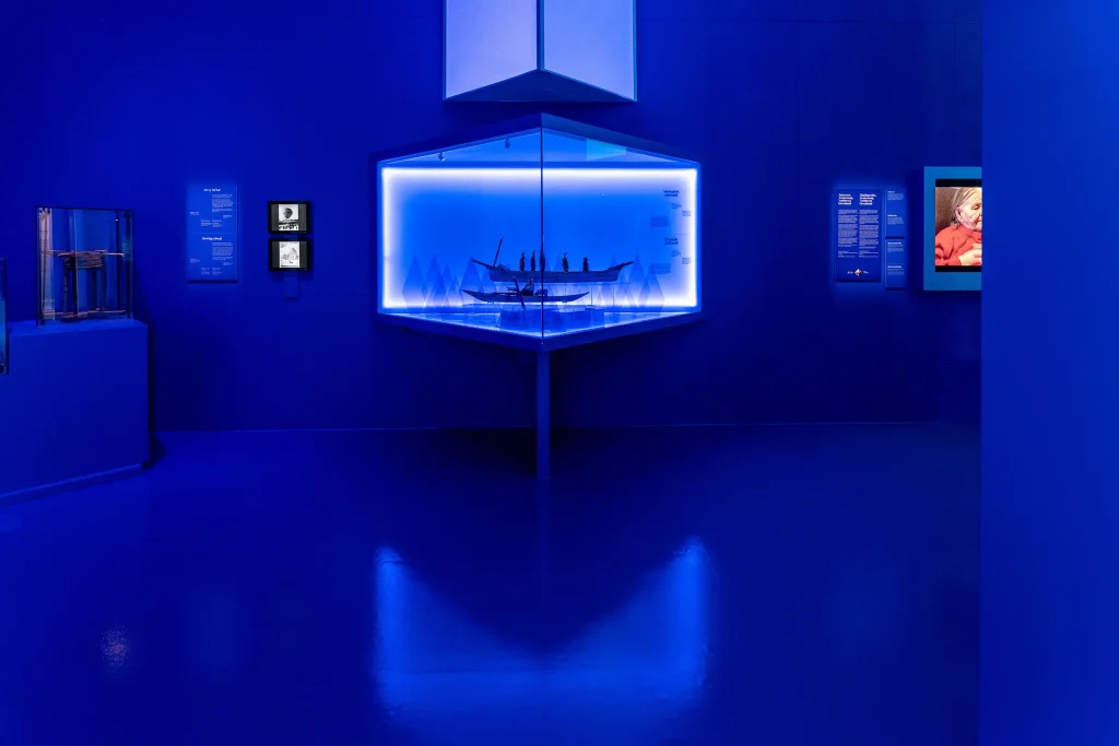 Ett starkt blått rum med en rombisk monter med två båtmodeller.
