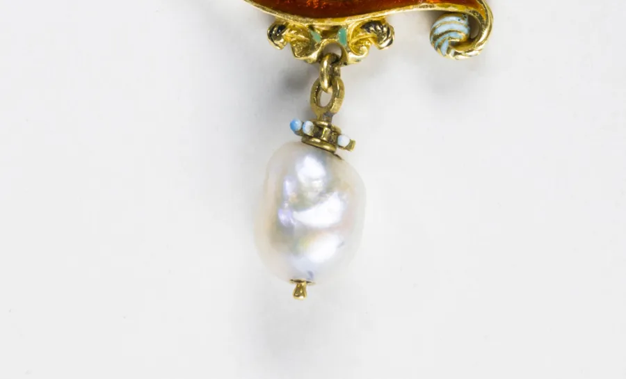 Ett halssmycke i en guldkedja, smycket är format som bokstaven C och har en safir och en pärla.