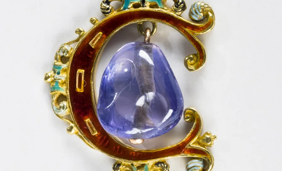 Ett halssmycke i en guldkedja, smycket är format som bokstaven C