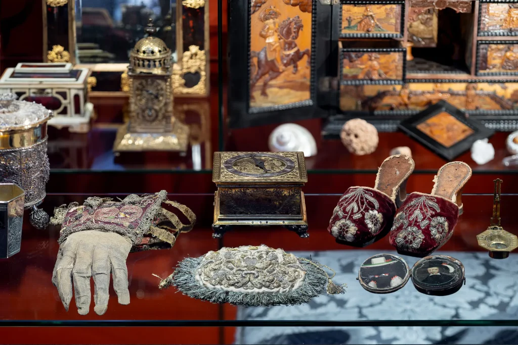 Närbild på många museiföremål som tofflor, handskar, askar och skrin.